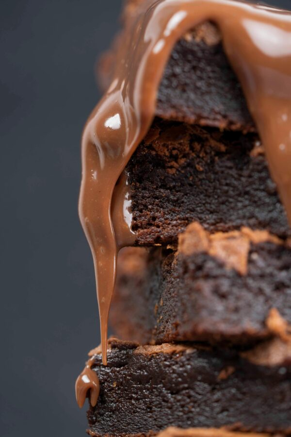 Close-up of a mouthwatering stack of brownies with melted chocolate dripping down.