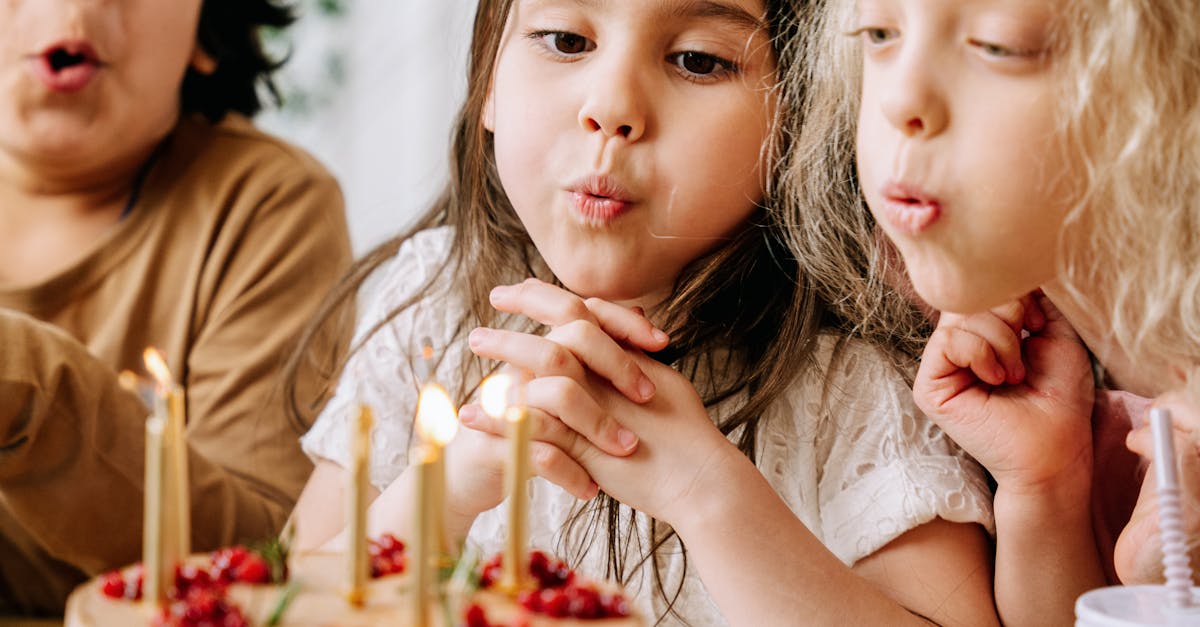 Children having fun blowing out candles on a birthday cake indoors.